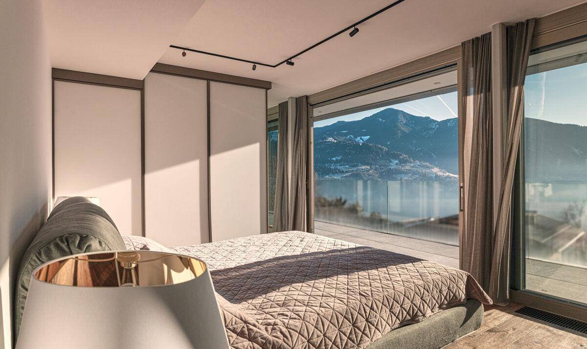 Modernes Schlafzimmer mit großen Glasfronten, die einen weiten Blick auf die Bergwelt bieten.