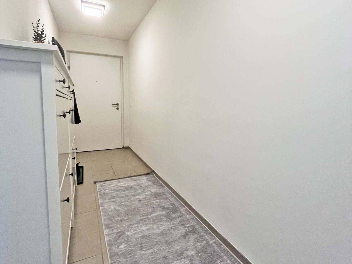 Heller Flur mit Fliesenboden und einem praktischen weißen Schrank im Eingangsbereich.