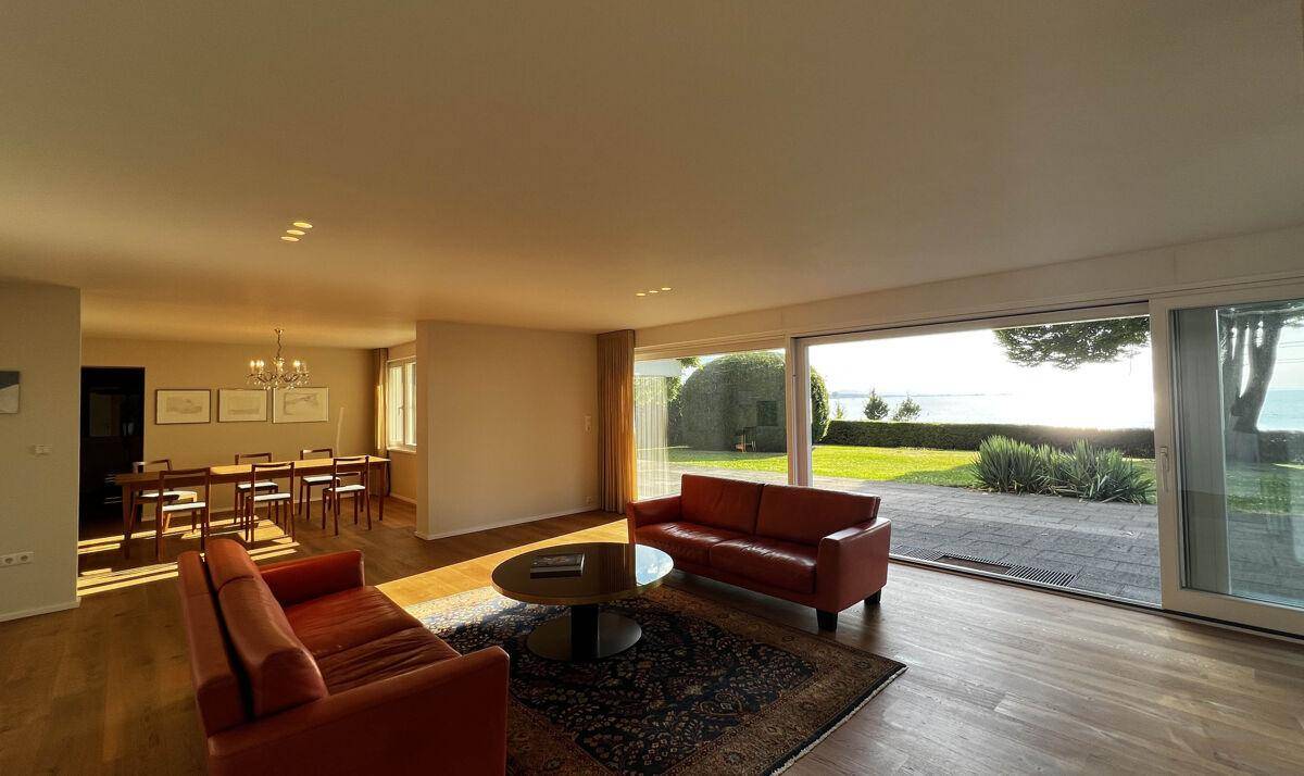 Helles Wohn- und Esszimmer mit Seeblick, Holzboden und modernen Ledersofas.