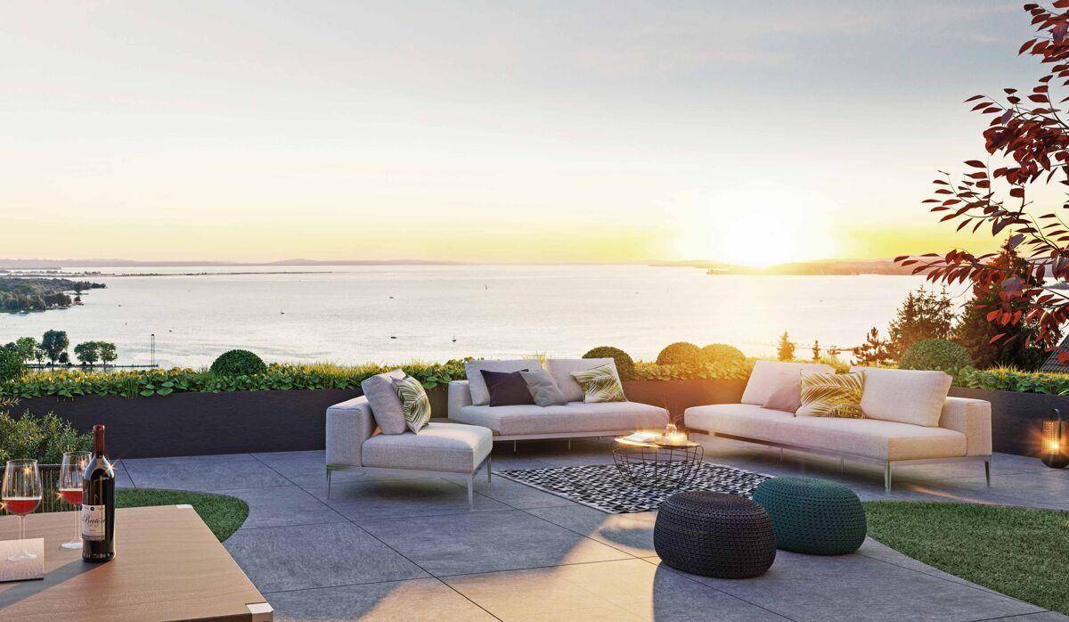 Großzügige Terrasse mit stilvollen Loungemöbeln und weitem Blick über den See bei Sonnenuntergang.