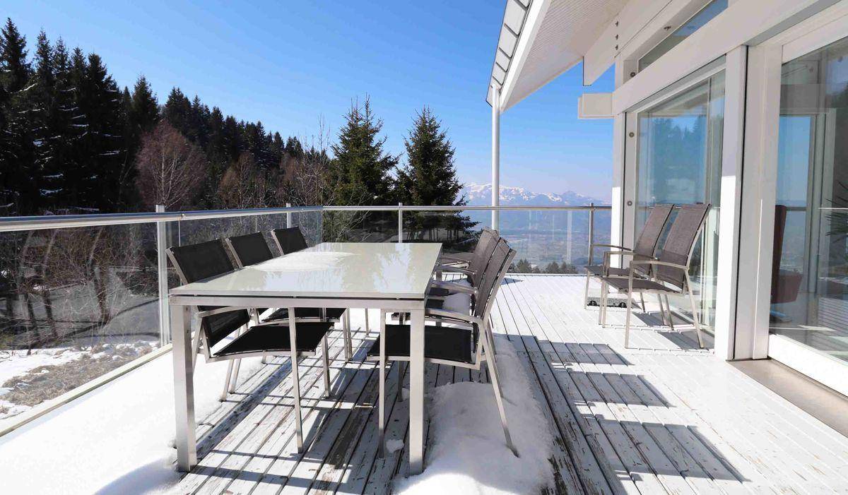 Geräumige Terrasse mit Esstisch und Stühlen, bietet einen weiten Blick auf die verschneite Berglandschaft.
