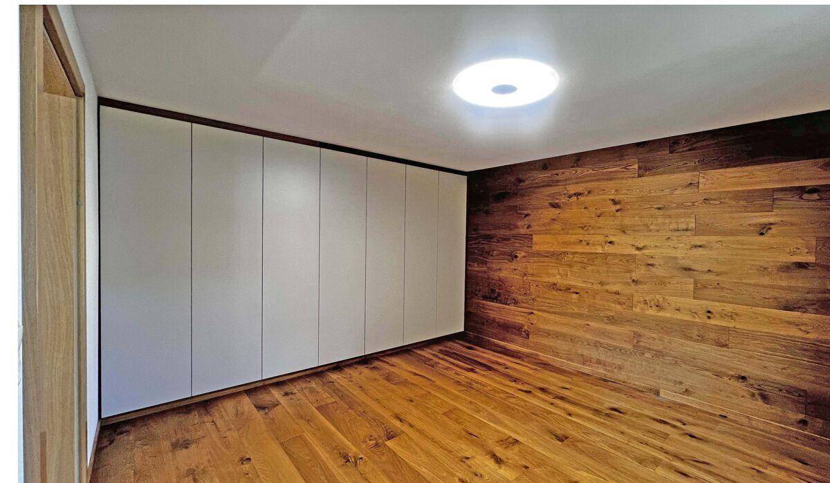 Modernes Schlafzimmer mit Holzboden und integriertem Wandschrank.