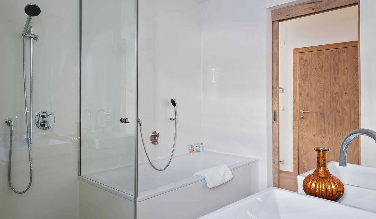 Helles Badezimmer mit Badewanne, integrierter Dusche und modernen Armaturen.