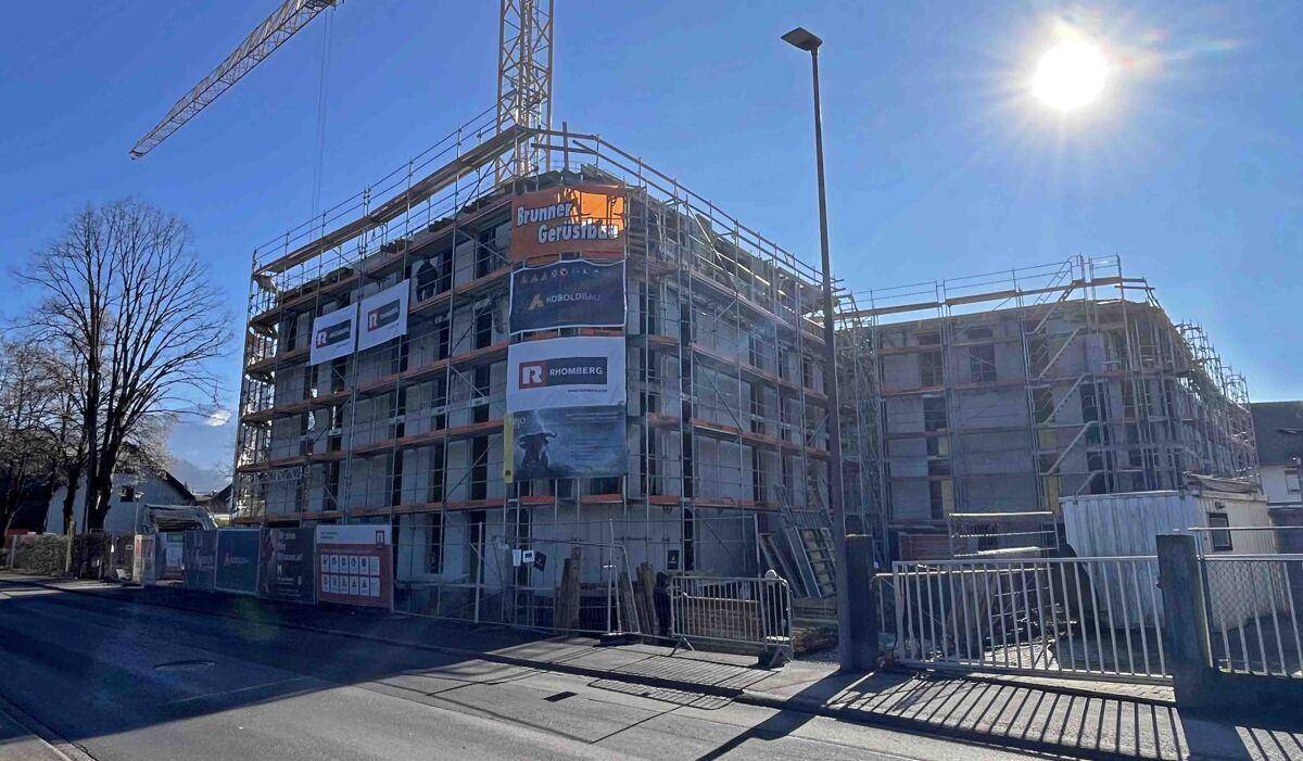 Neubau in der Bauphase mit Gerüst und Kran unter strahlendem Sonnenschein.