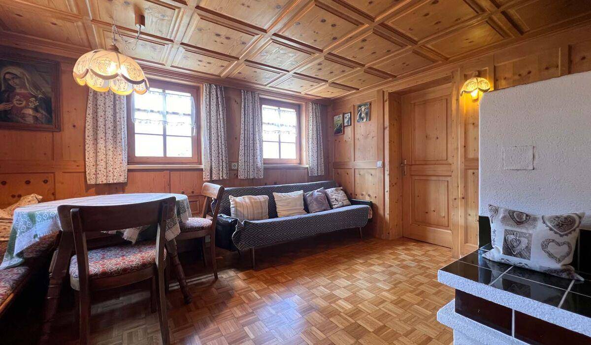 Gemütlicher Wohnbereich im Landhausstil mit Holztäfelung, Parkettboden und Kachelofen.