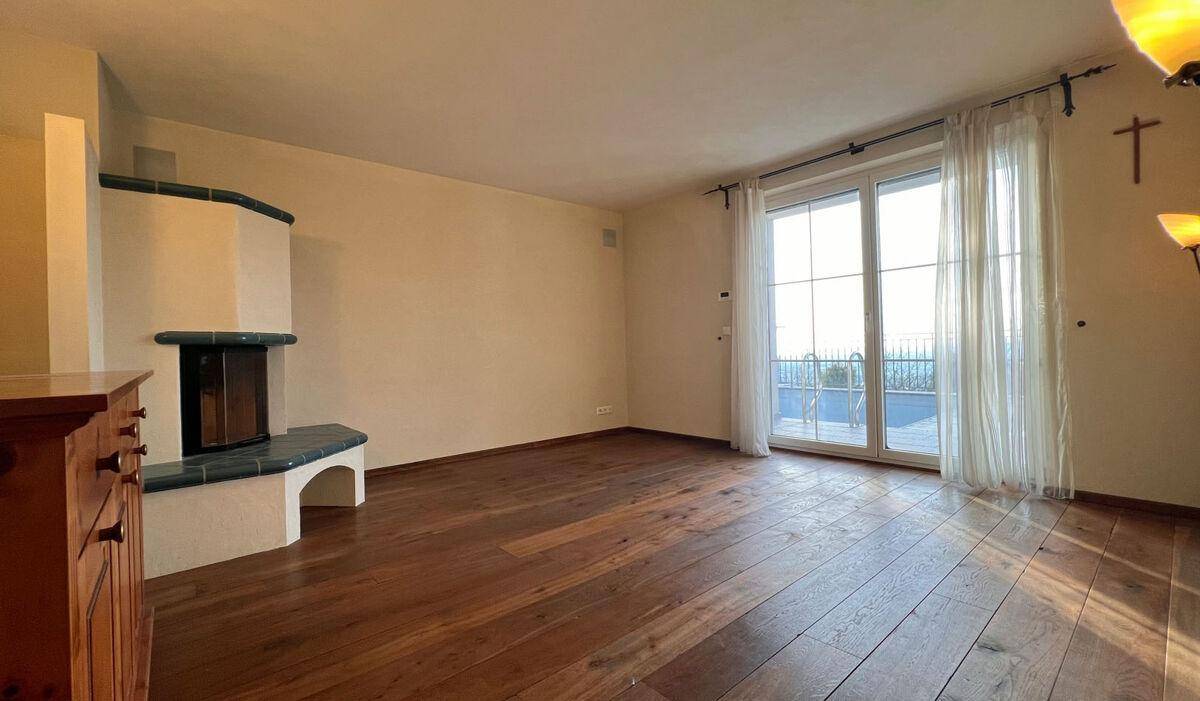 Gemütliches Wohnzimmer mit Kamin, Holzboden und großen Fenstern mit Blick ins Freie.