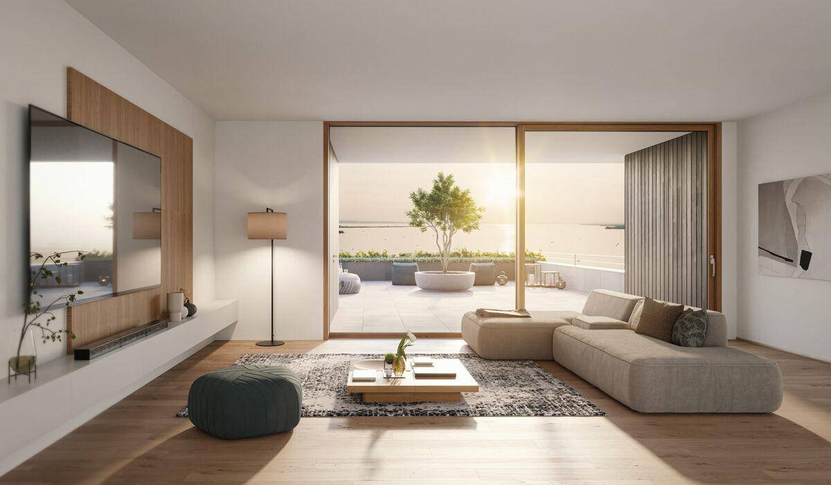 Helles Wohnzimmer mit großen Schiebetüren, die zu einer Terrasse mit Seeblick führen.