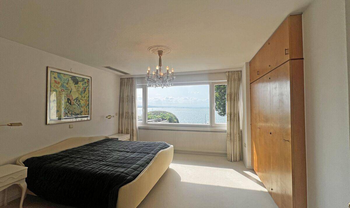 Helles Schlafzimmer mit Seeblick, großem Fenster und integriertem Holzschrank.