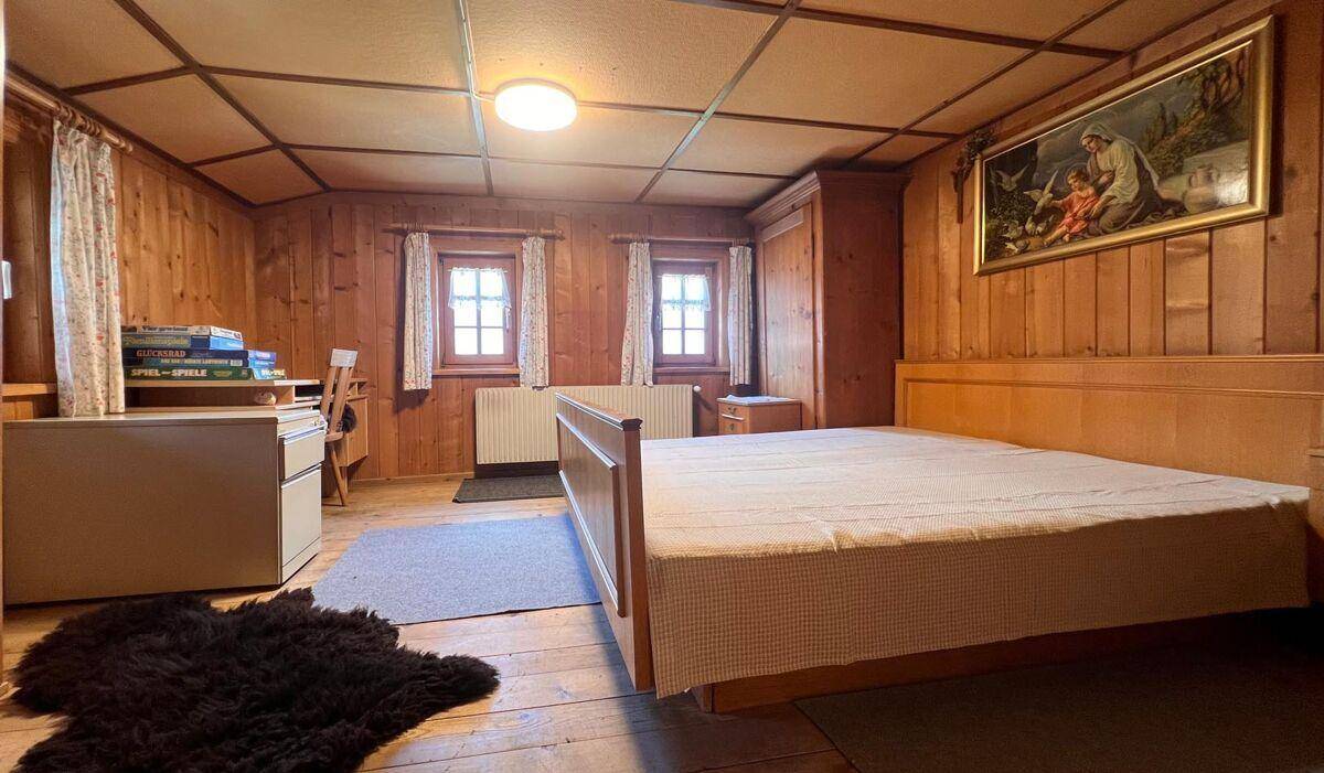 Geräumiges Schlafzimmer mit Holzboden, Holzwänden und einem großen Doppelbett.