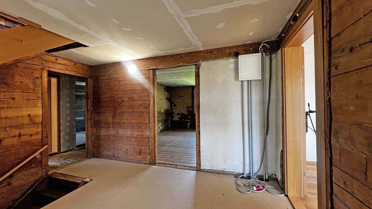 Innenbereich in Renovierung mit Holzwänden und sichtbaren Installationen.