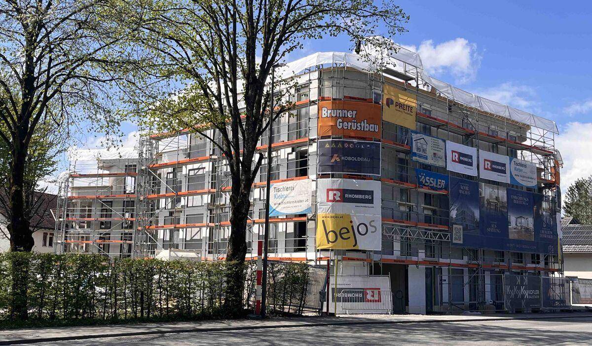 Gebäude im Bau mit Gerüst und Werbebannern von Baufirmen an der Fassade.