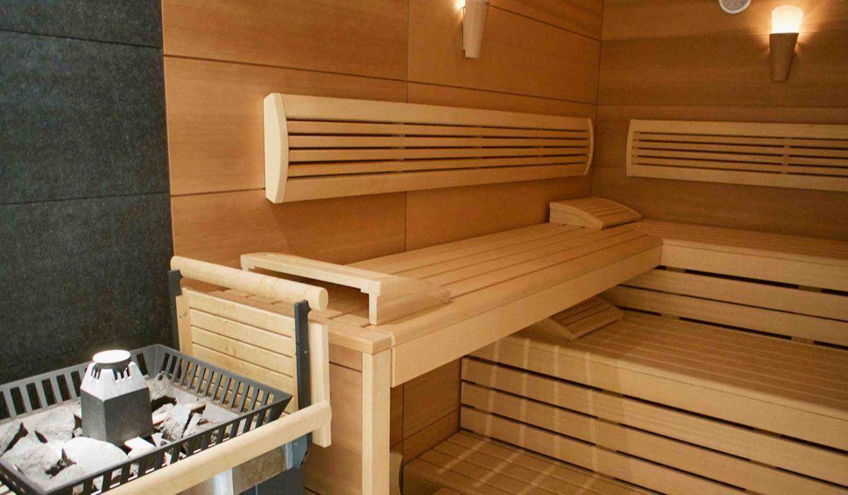 Moderne Holzsauna mit mehreren Bänken und Heizofen für entspannende Wellnessmomente.