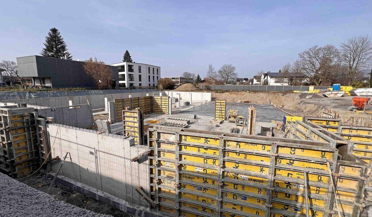 Baustelle mit ausgehobener Grube und Betonfundamenten für ein neues Gebäude.