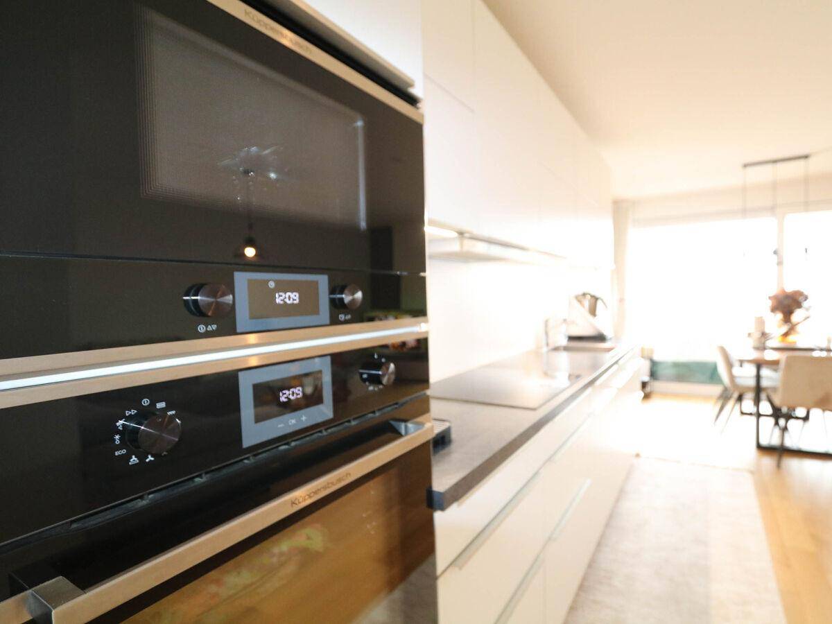 Moderne Küchengeräte mit integriertem Backofen und Mikrowelle in einer hellen Küche.
