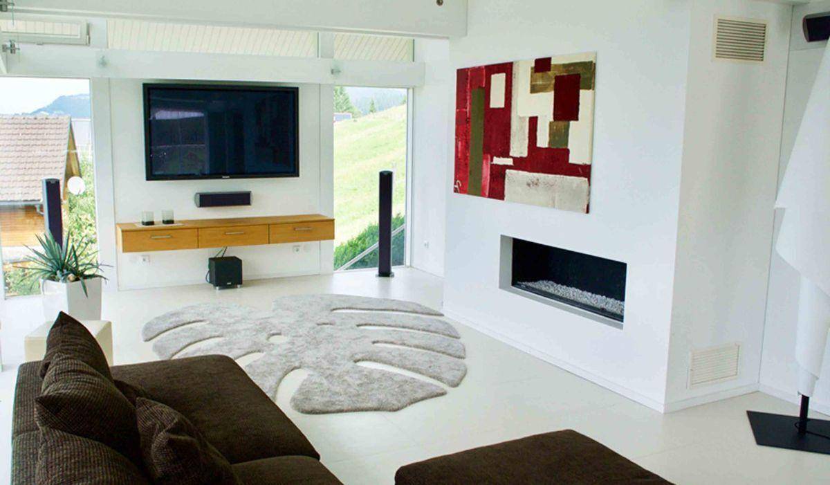 Modernes Wohnzimmer mit integriertem Kamin, großem Fernseher und minimalistischer Einrichtung.