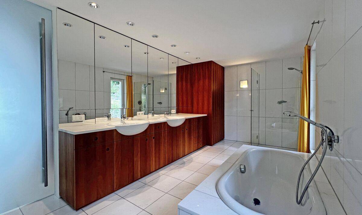 Geräumiges Badezimmer mit Doppelwaschbecken, Badewanne, Dusche und großen Spiegelflächen.