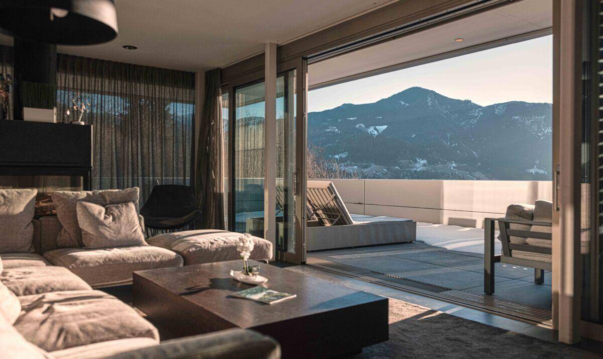 Geräumiges Wohnzimmer mit bequemen Sofas, großen Schiebetüren und Bergblick von der Terrasse.