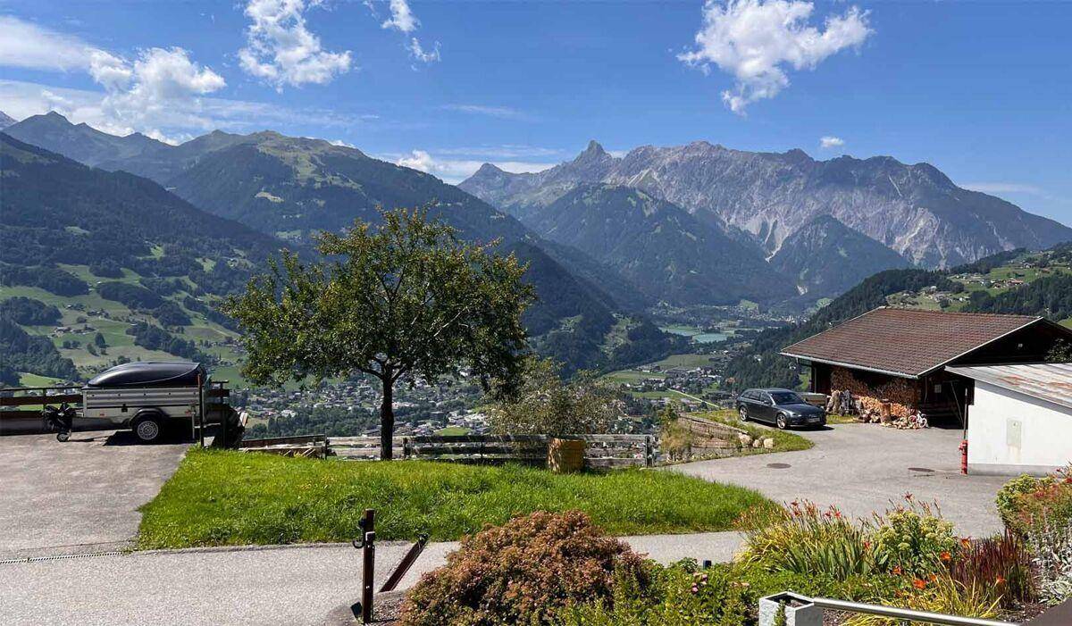 Atemberaubender Bergblick mit weitem Tal und einem See in der Ferne unter blauem Himmel.