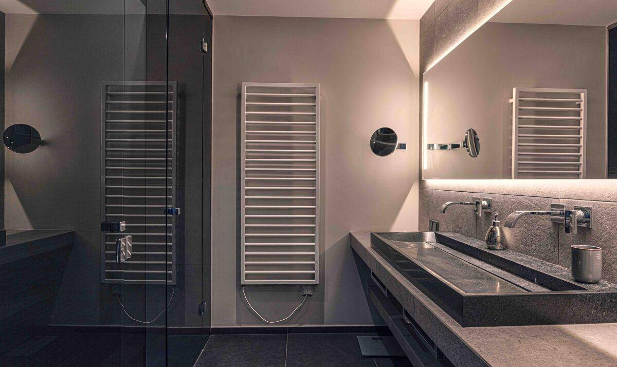 Modernes Badezimmer mit Doppelwaschbecken, großer Dusche und beheiztem Handtuchhalter.