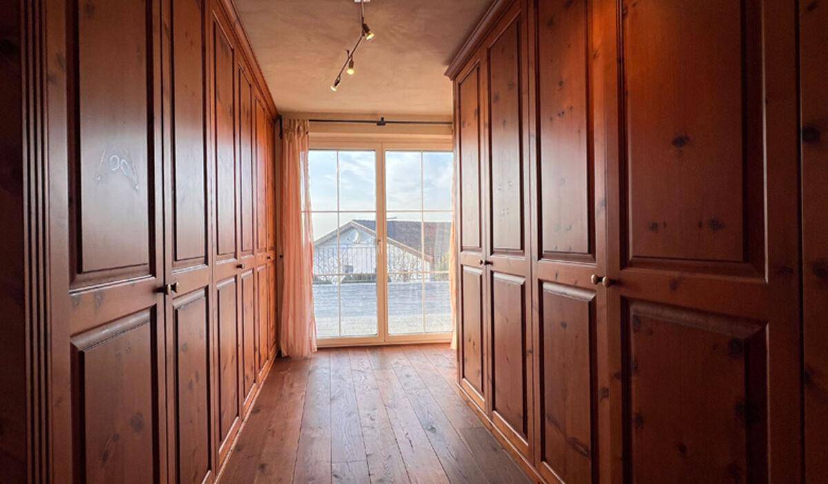 Langer Flur mit maßgefertigten Einbauschränken und Fenster am Ende für Tageslicht.