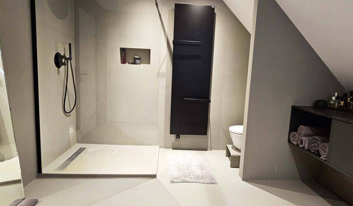 Modernes Badezimmer mit ebenerdiger Dusche, Wand-WC und beheiztem Handtuchhalter im Dachgeschoss.