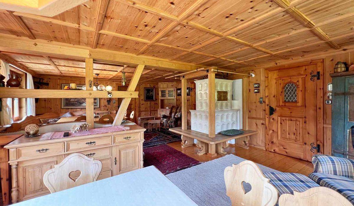 Gemütlicher Wohn- und Essbereich im Alpenstil mit Holztäfelung, Kachelofen und traditionellen Möbeln.
