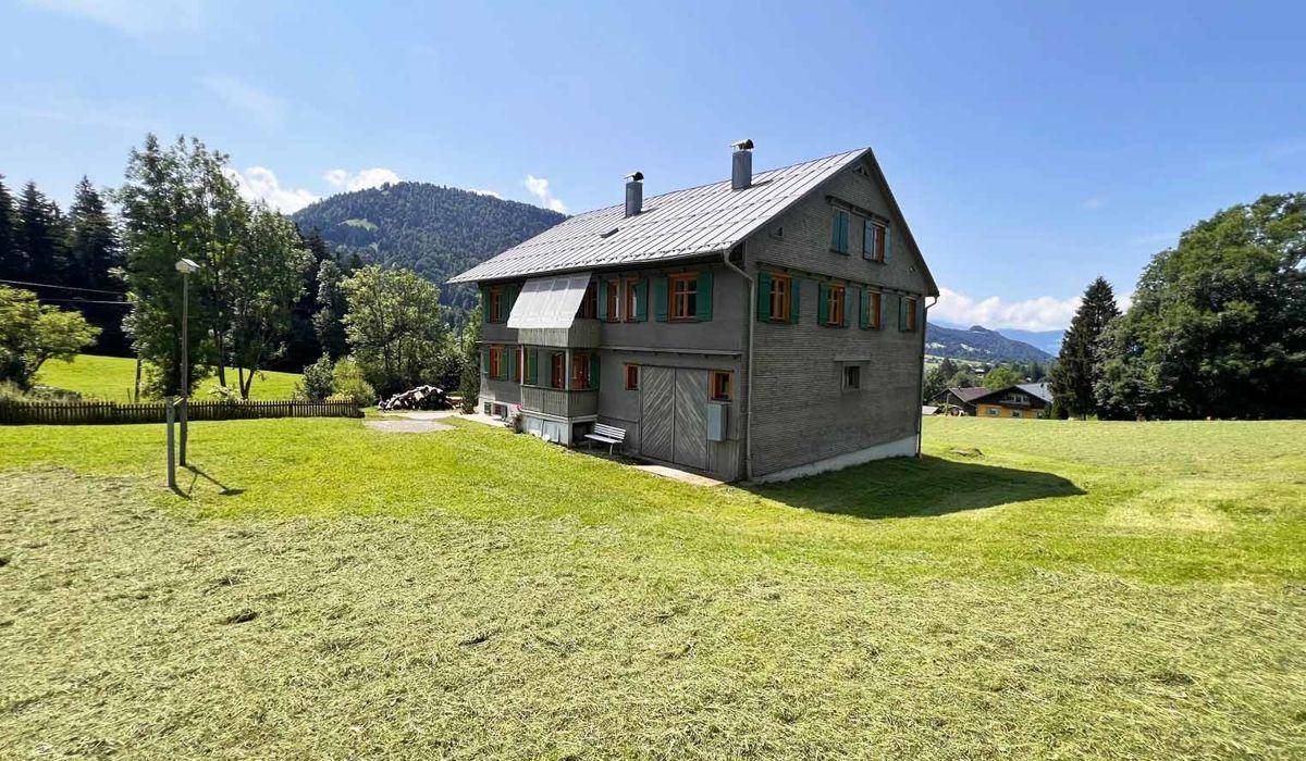 Großzügige Rasenfläche um das traditionelle Alpenhaus mit Blick auf die umliegende Berglandschaft.