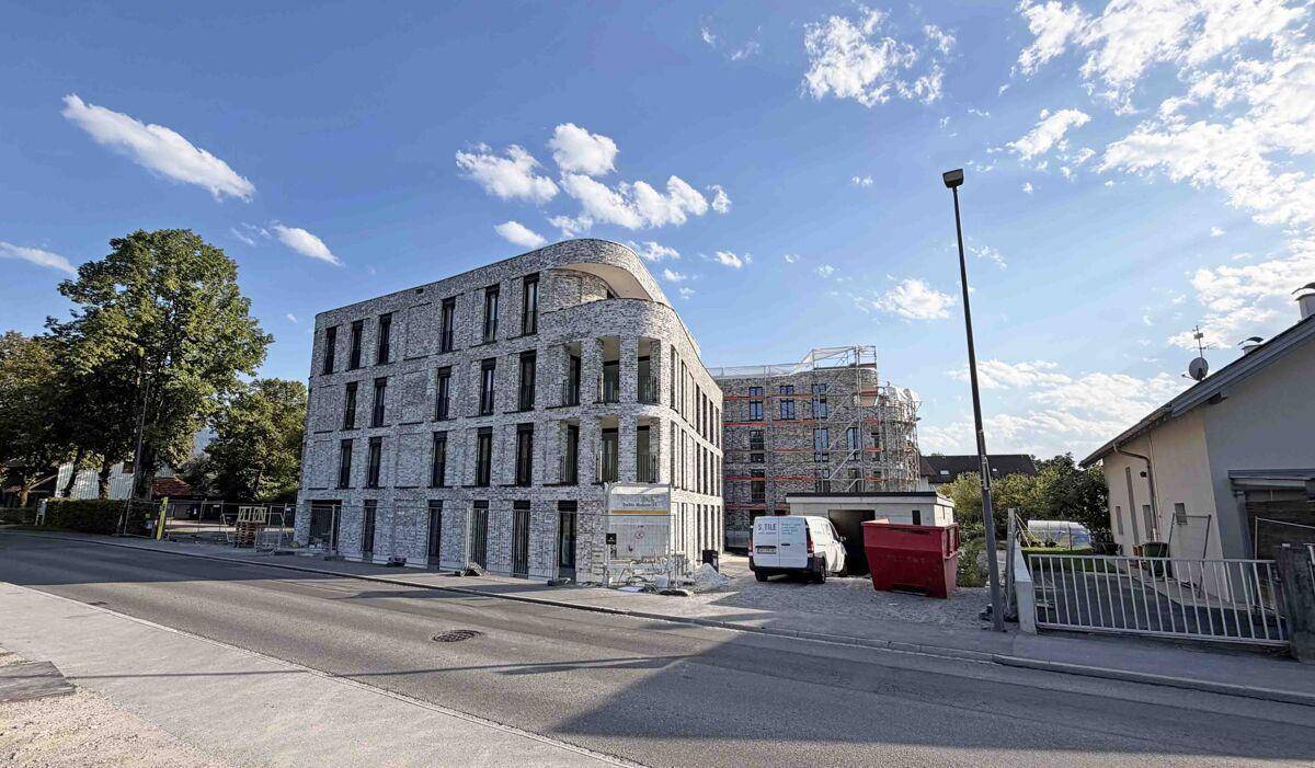 Ansicht des modernen Neubaus mit geschwungener Fassade und Baustellenelementen in der Umgebung.