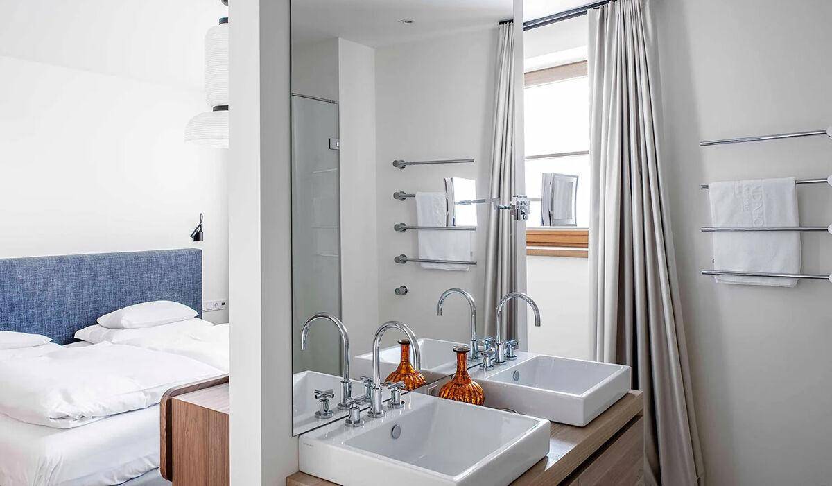 Modernes Badezimmer mit Doppelwaschbecken, großem Spiegel und direktem Zugang zum Schlafbereich.
