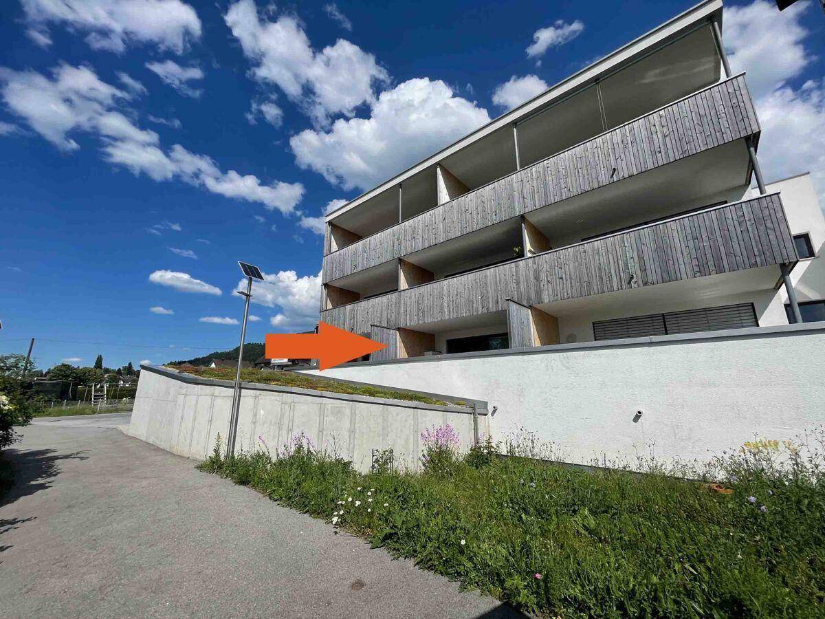 Moderne Wohnanlage mit mehreren Balkonen und Holzverkleidung unter blauem Himmel.