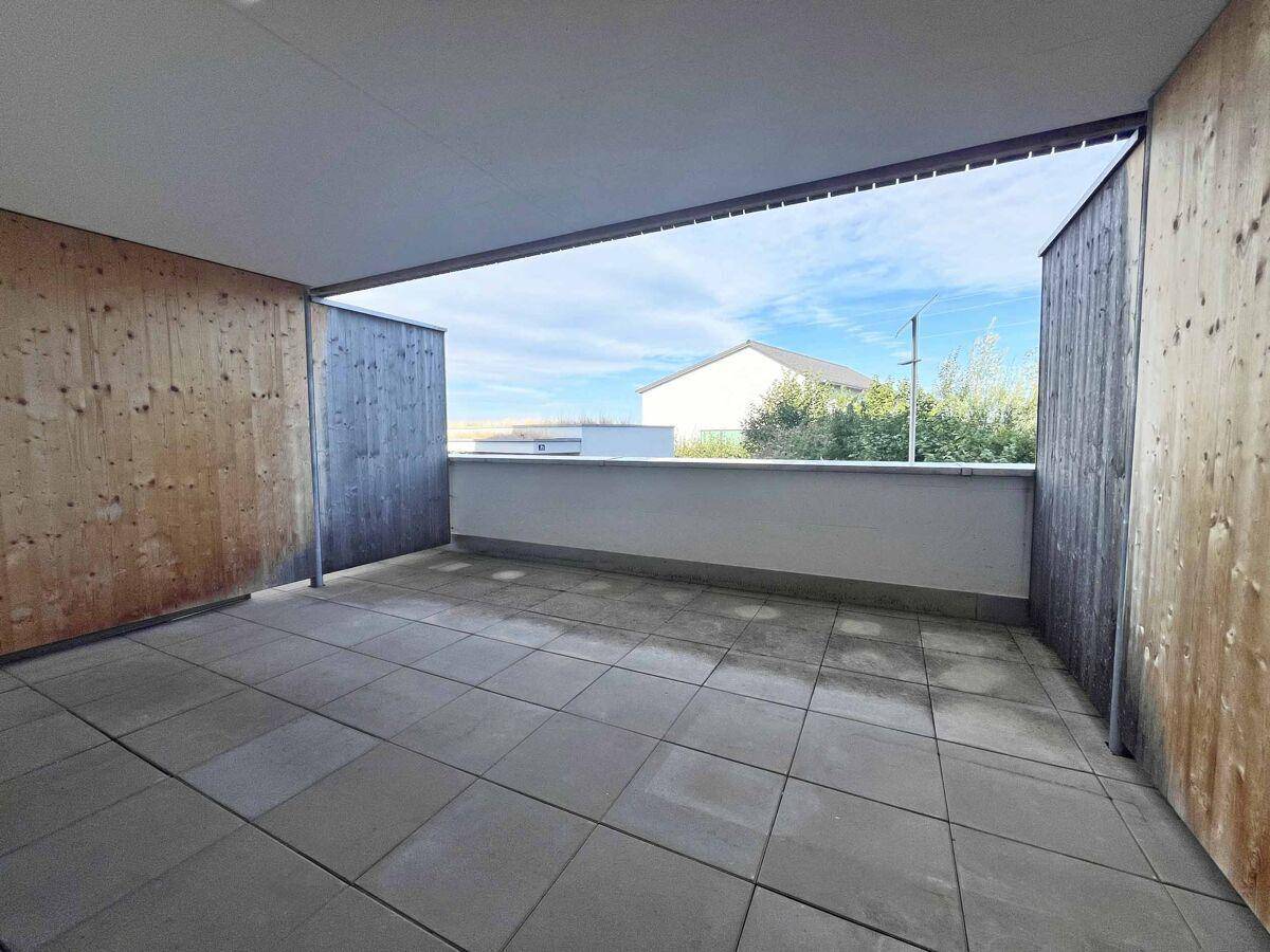 Geräumiger Balkon mit Fliesenboden und Holzwänden, bietet einen weiten Blick ins Grüne.