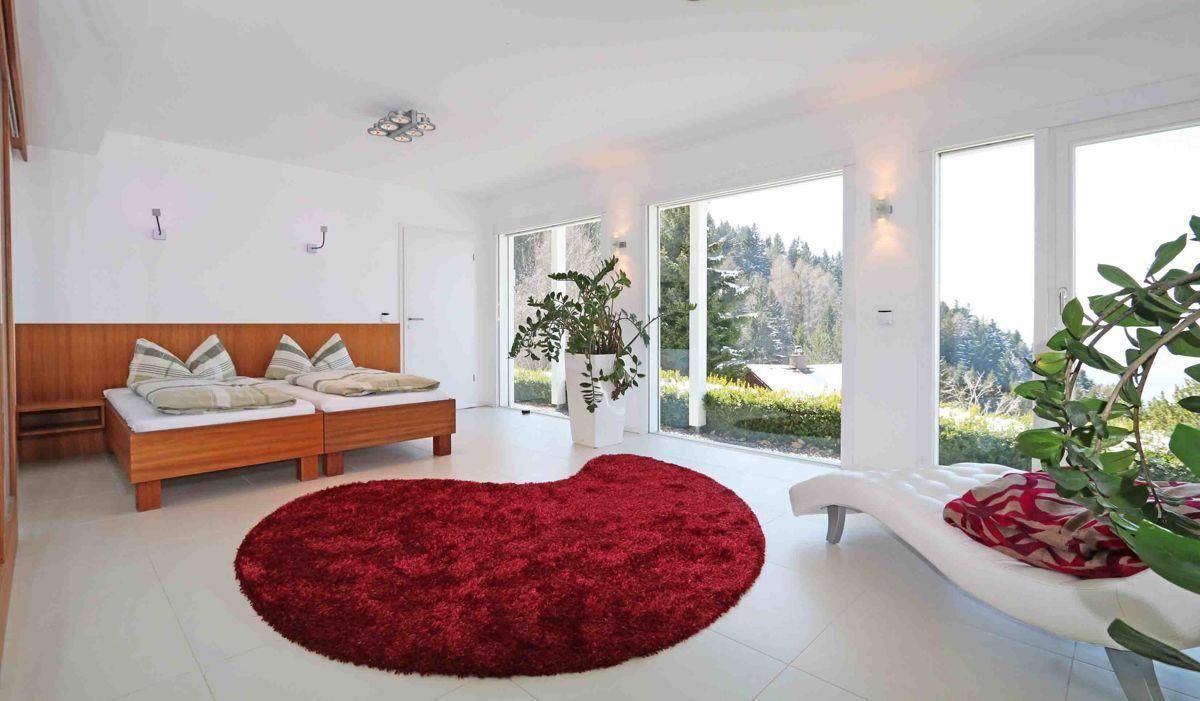 Helles Schlafzimmer mit zwei Einzelbetten, großen Fenstern und Blick ins Grüne.