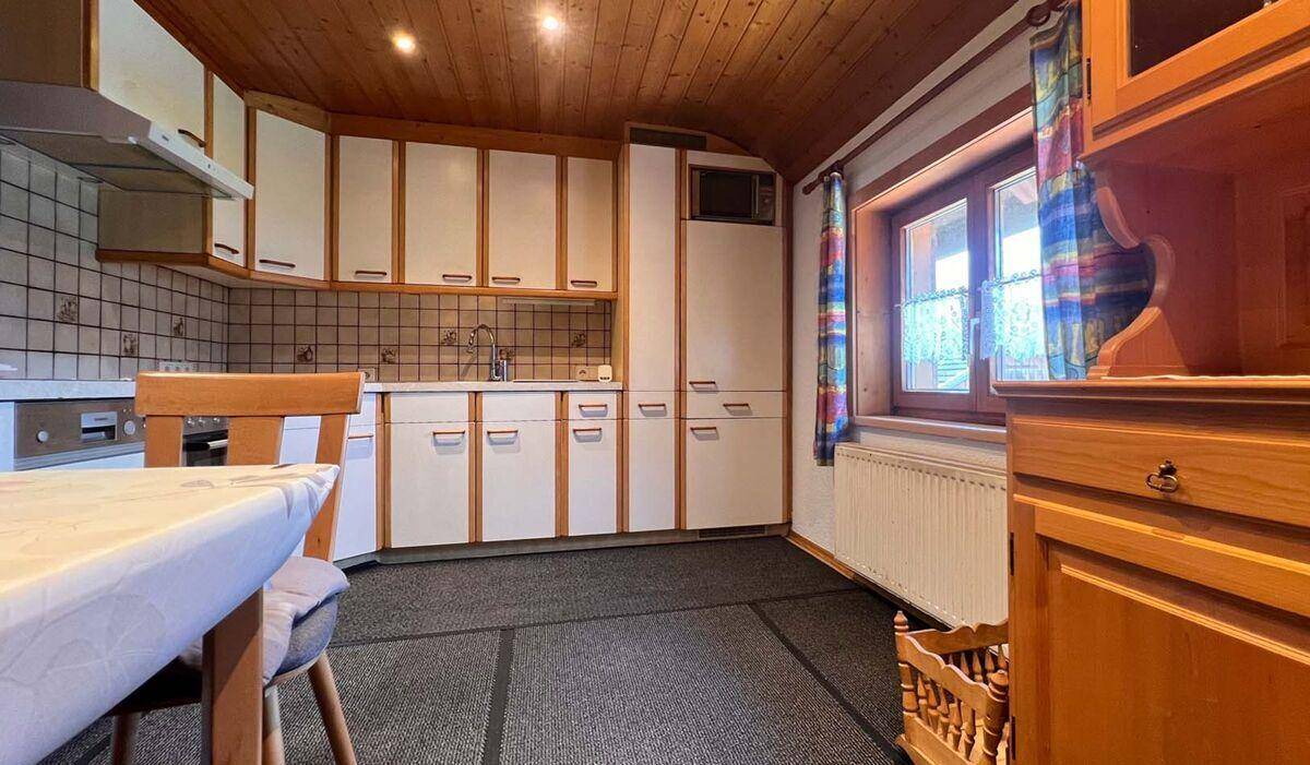 Traditionelle Küche mit weißen Schränken, Fliesenrückwand und Essbereich.