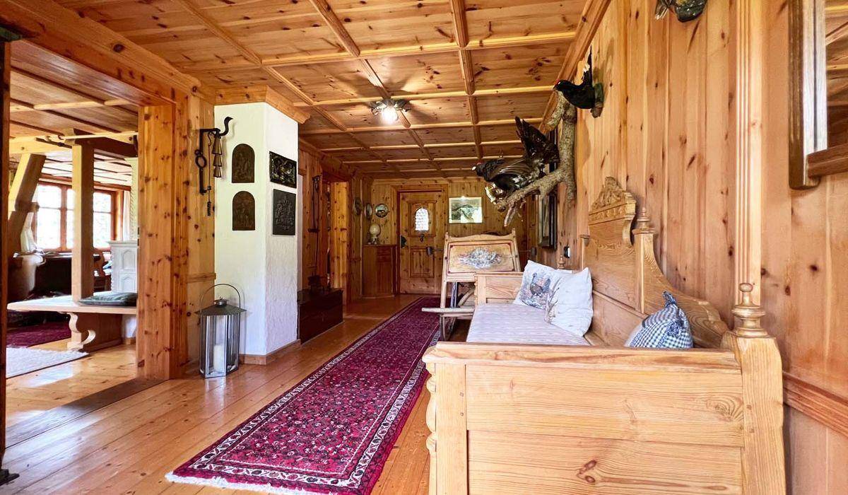 Langer Flur im Alpenstil mit Holzboden, Holztäfelung und traditionellen Möbeln und Dekorationen.