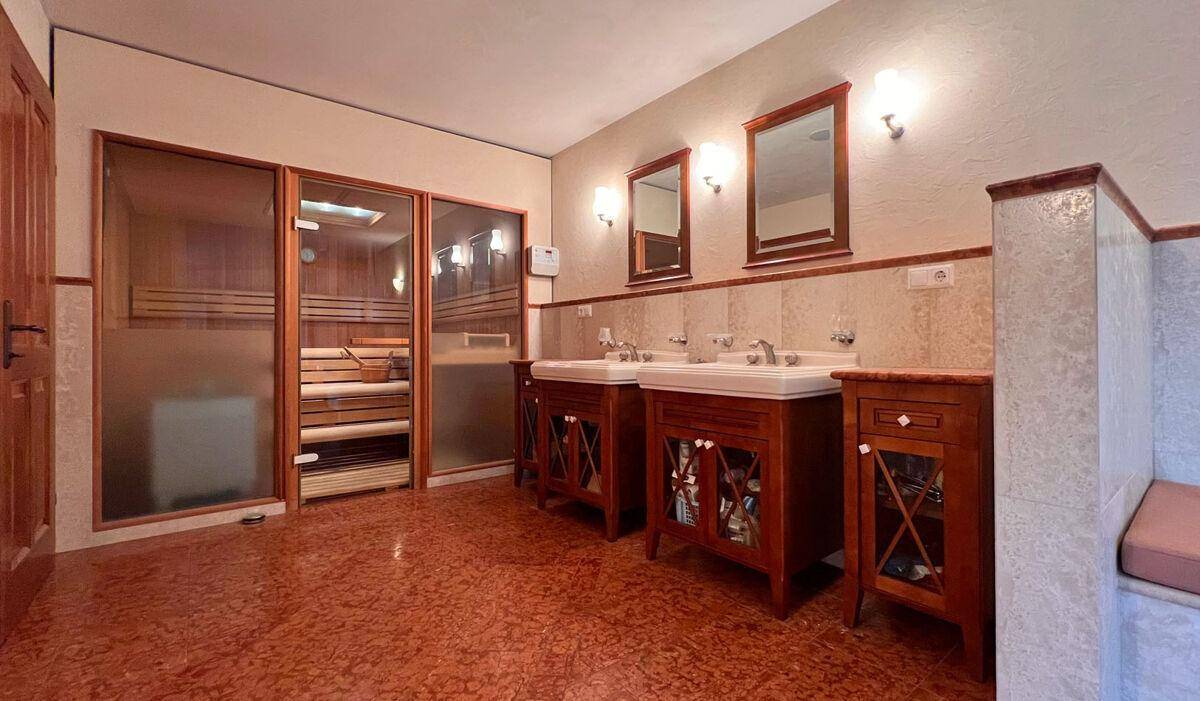 Modernes Badezimmer mit Sauna, Doppelwaschbecken und stilvollen Fliesen.