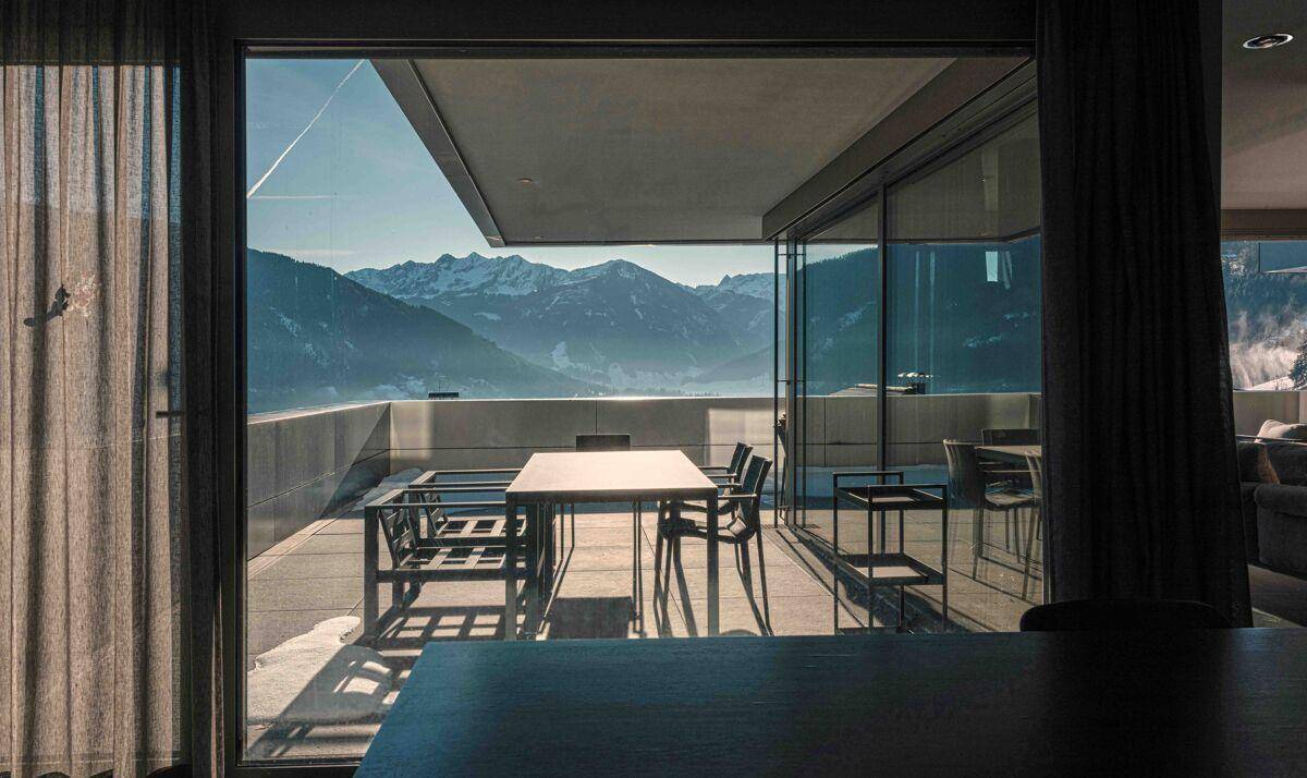 Große, sonnige Terrasse mit modernen Gartenmöbeln und beeindruckendem Bergblick.