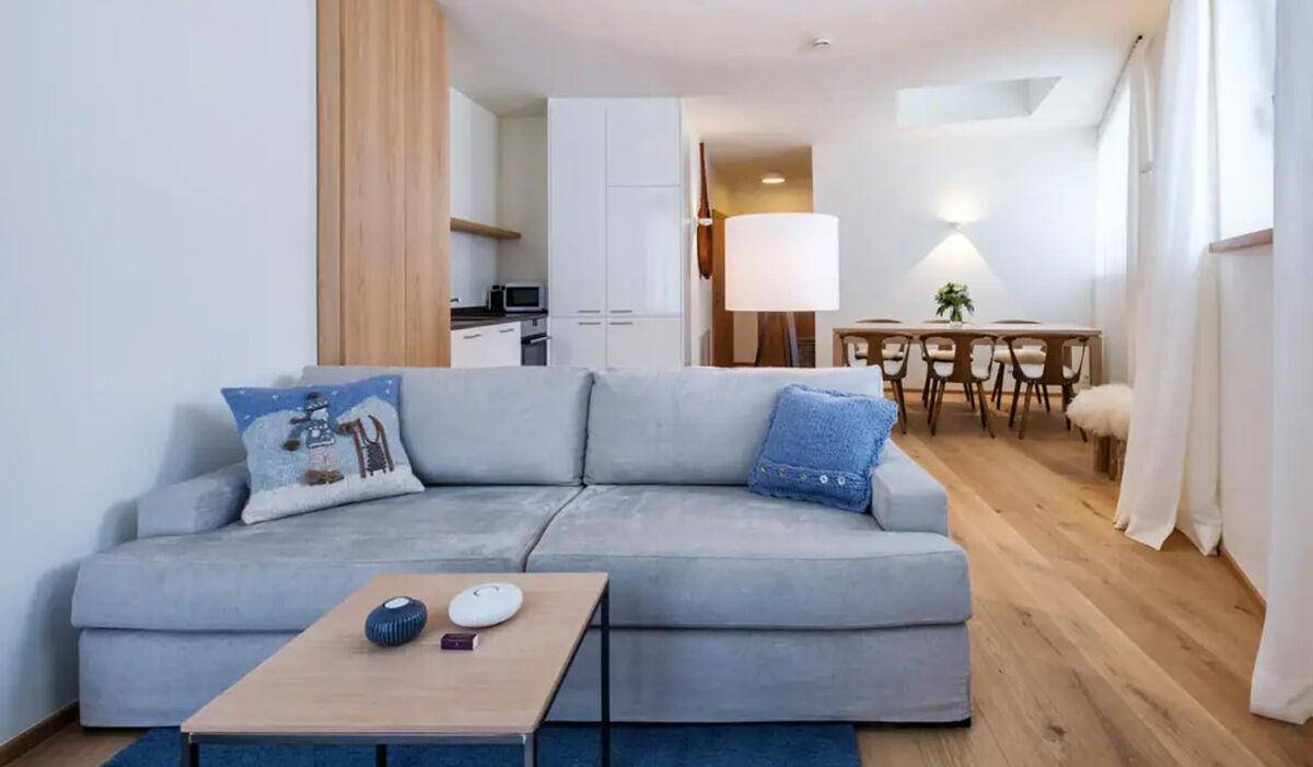Heller offener Wohn- und Essbereich mit bequemem Sofa, Holzboden und integrierter Küchenzeile.