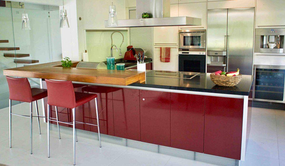 Moderne Küche mit roter Kücheninsel, Holzarbeitsplatte und hochwertigen Einbaugeräten.