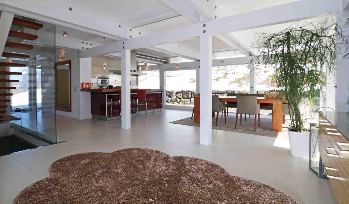 Offener Wohnbereich mit Essbereich und Küche, verbunden durch eine moderne Treppe und große Fenster.