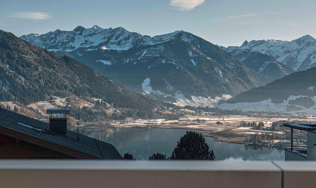 Panoramablick auf verschneite Berge und einen See von der erhöhten Position des Anwesens.