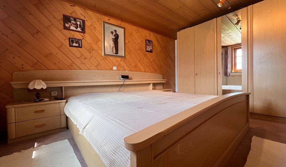 Schlafzimmer mit hellem Holzdoppelbett, Einbauschränken und Holzwänden im Landhausstil.