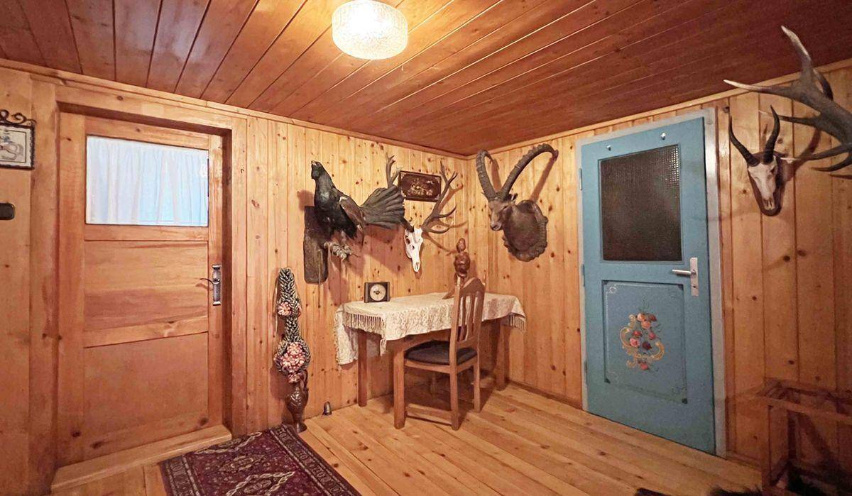 Rustikaler Flur mit Holztäfelung, traditionellen Türen und Jagdtrophäen als Dekoration.