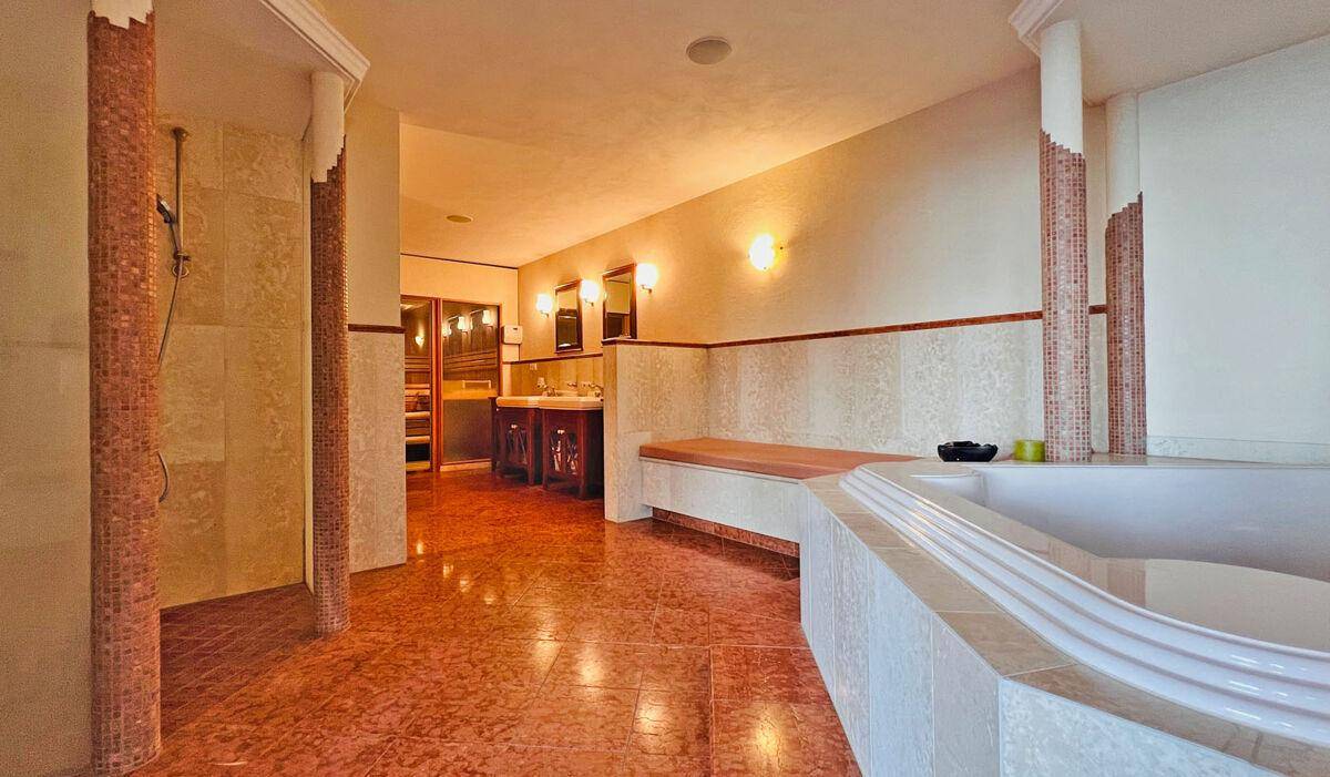 Großzügiges Badezimmer mit Badewanne, Dusche und Wellnessbereich mit Sauna.