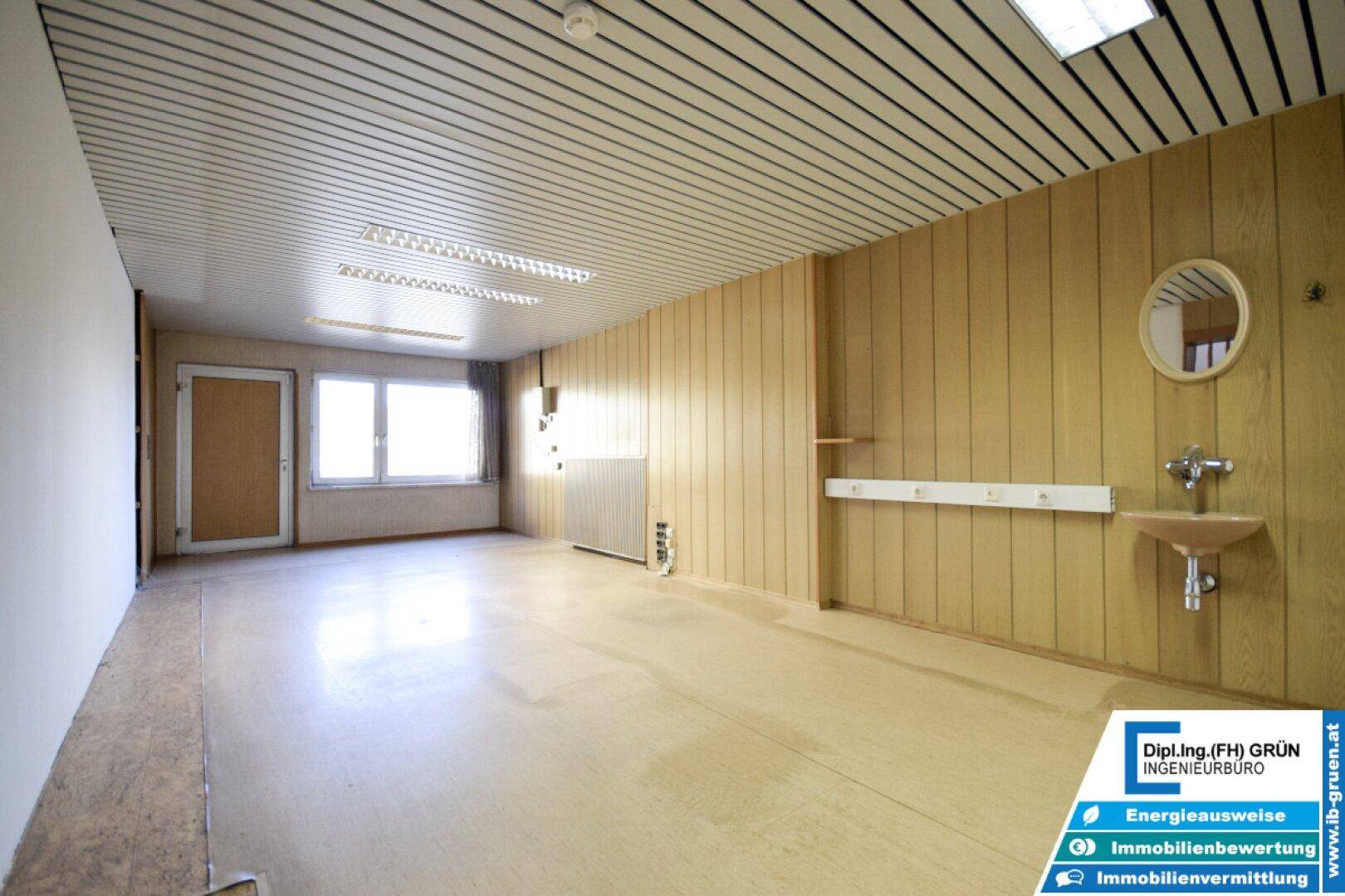 Geräumiger, leerer Raum mit Holzvertäfelung, Waschbecken und Fenstern, ideal für vielseitige Nutzung.