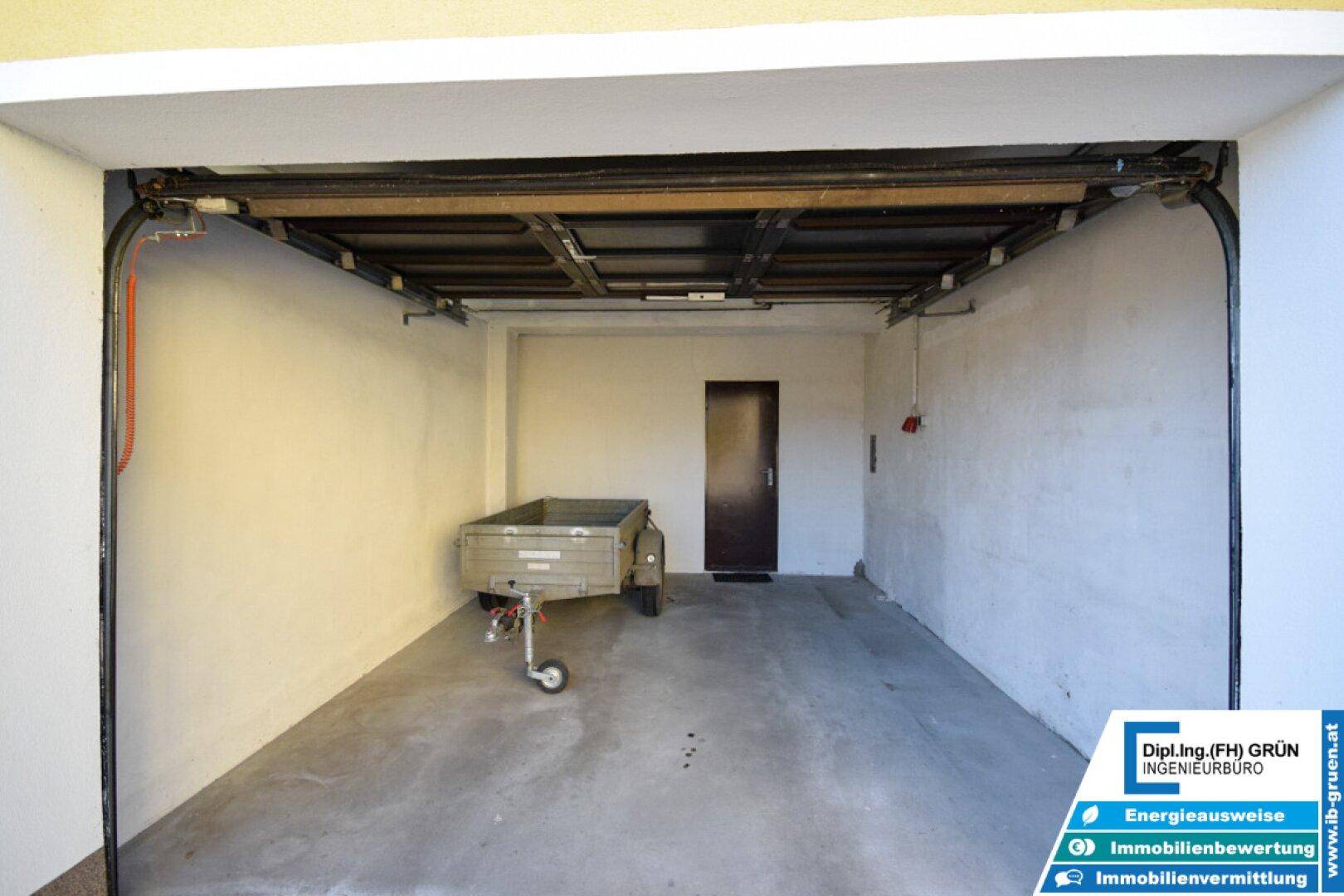 Leere Garage mit Betonboden und einem kleinen Anhänger, bereit zur Nutzung.