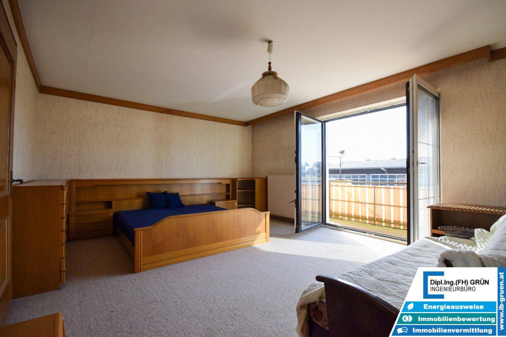 Schlafzimmer mit Teppichboden, Holzmöbeln und Zugang zu einem Balkon oder einer Terrasse.