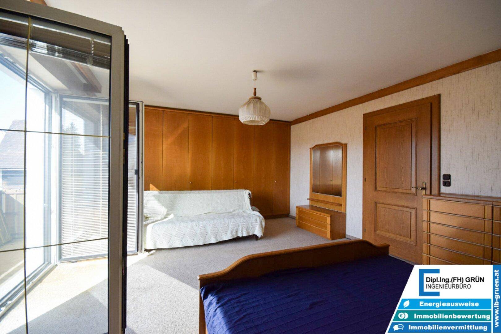 Schlafzimmer mit eingebauten Holzschränken, Sofa und Zugang zum Außenbereich.