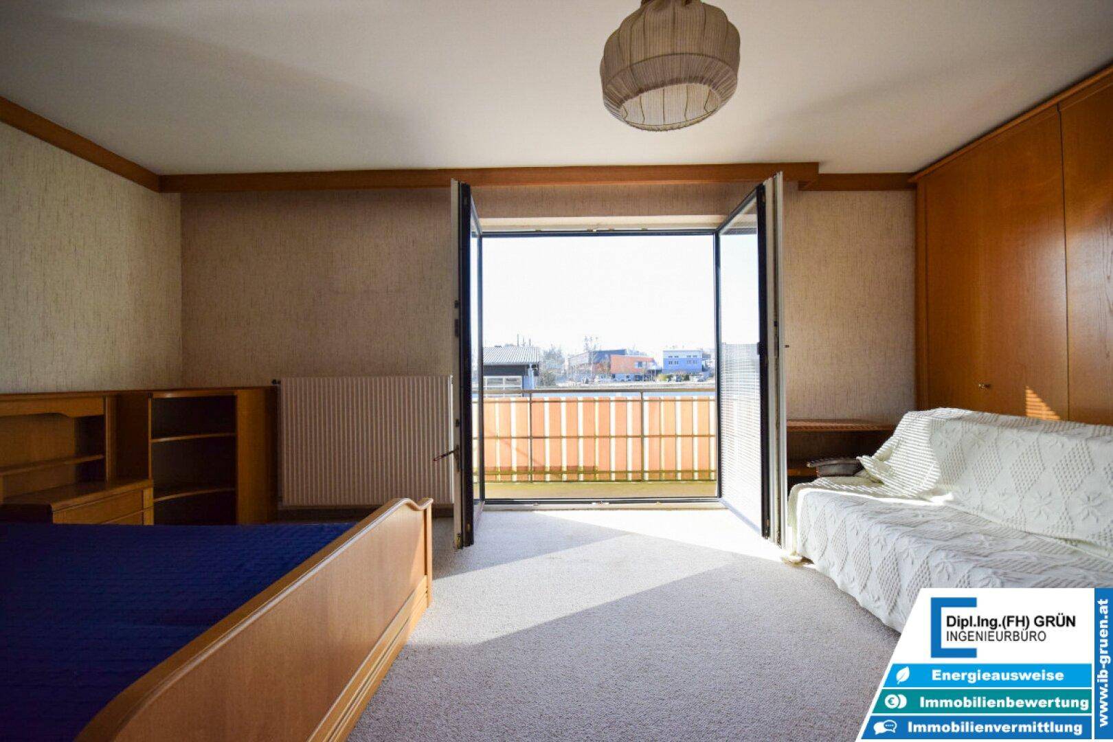 Schlafzimmer mit weitem Blick vom Balkon auf die Umgebung und andere Gebäude.