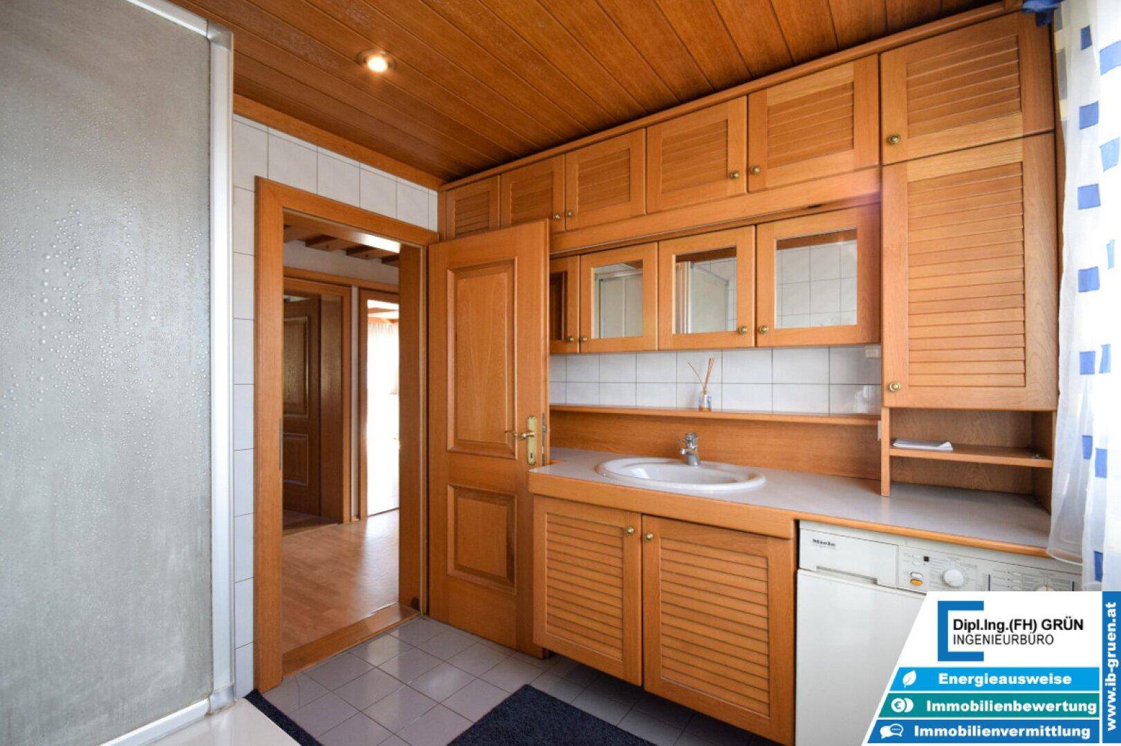 Badezimmer mit Holzwaschtisch, integrierter Waschmaschine und Holzdecke.
