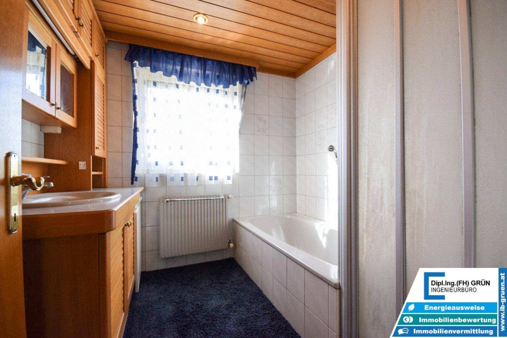 Badezimmer mit Badewanne, Holzwaschtisch und Holzdecke, traditionell gefliest.